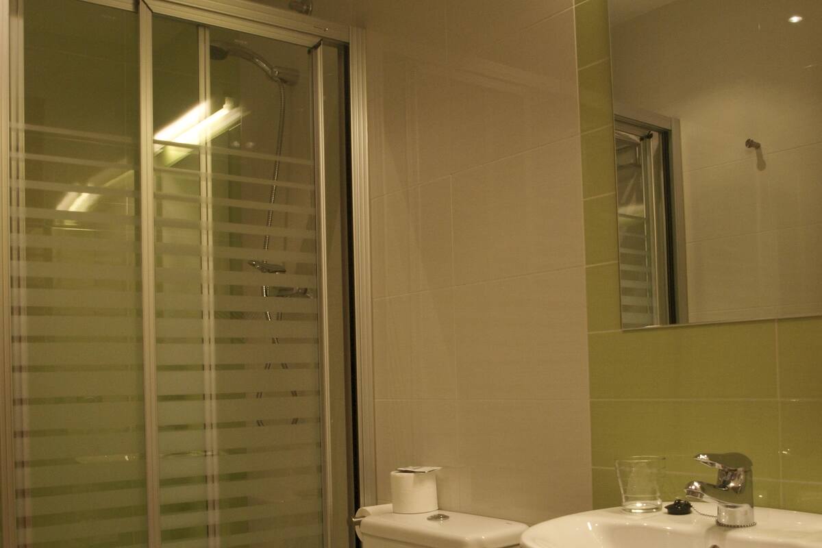 Un baño con inodoro, lavamanos y ducha con puerta de cristal.