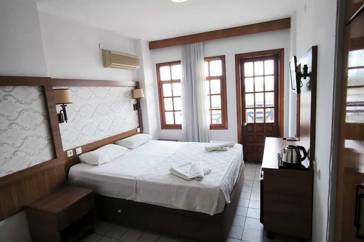 Una habitación de hotel con cama, escritorio, silla, ventana y puerta.