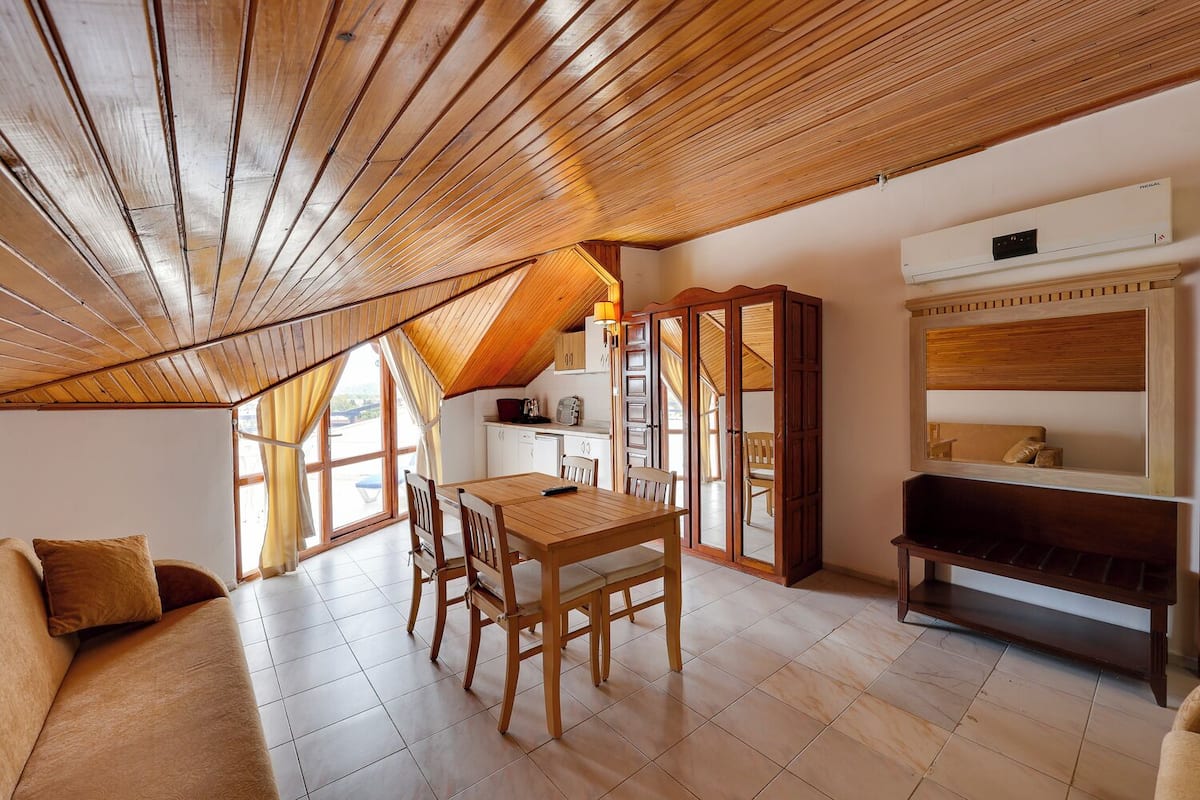 Una habitación acogedora con techo de madera, una mesa de comedor con sillas, un sofá y un banco empotrado.