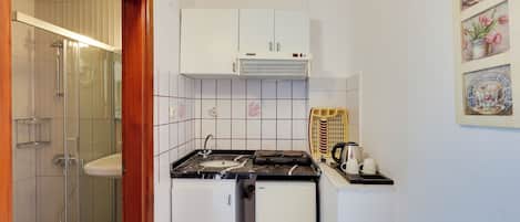 A compact kitchen with a stove, sink, and a small refrigerator.