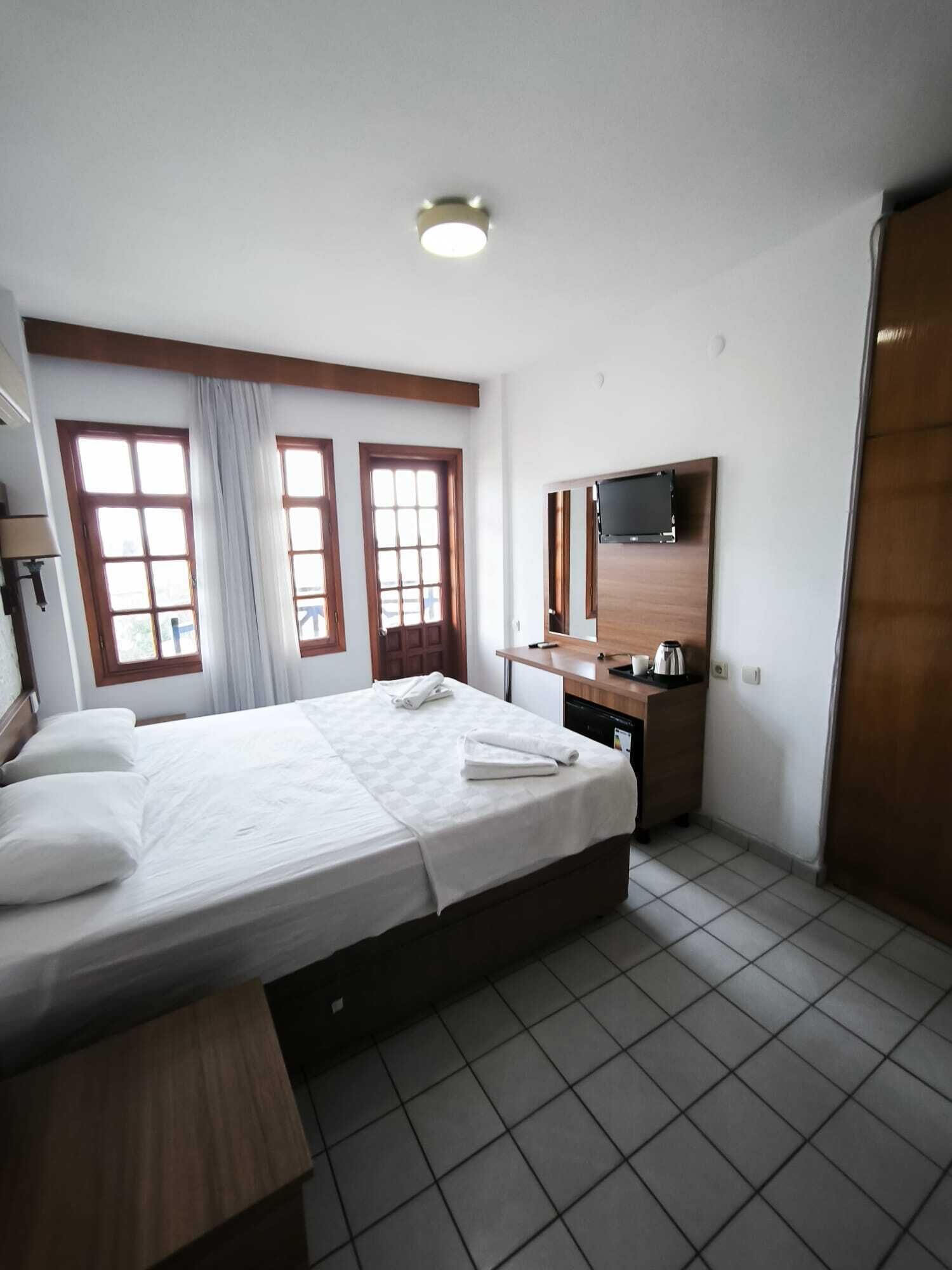 A hotel room with a bed, a desk, a television, and a bathroom.