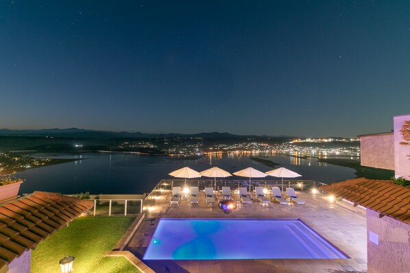 Een buitenzwembad, parasols bij het zwembad en ligstoelen