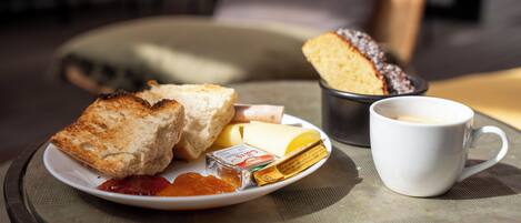 A breakfast setting with toast, butter, jam, cheese, and a cup of coffee on a table.
