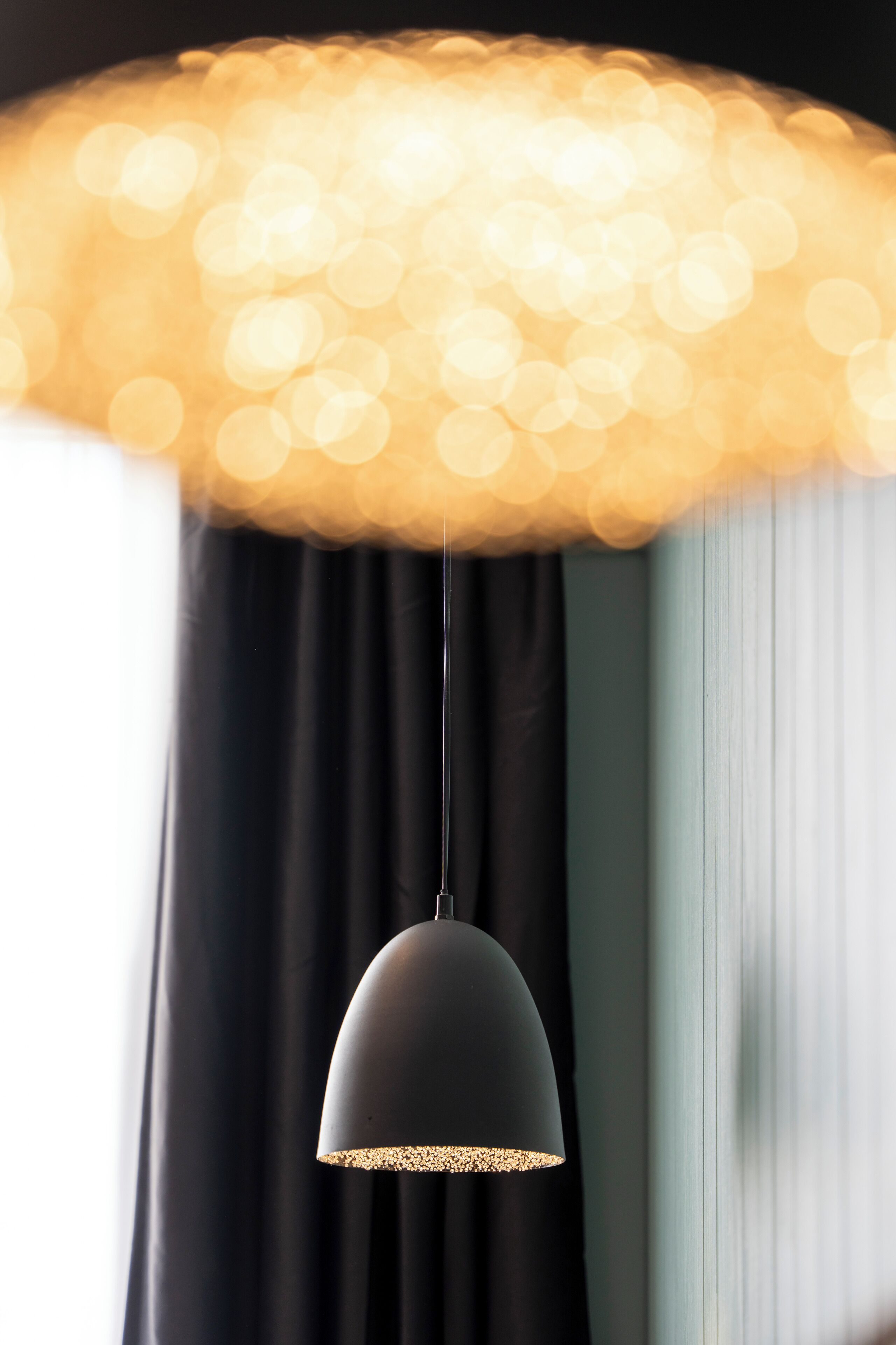 A pendant light with a textured shade and a gold rim, hanging from a ceiling.