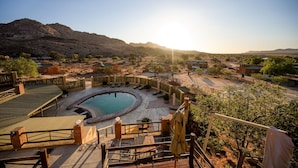 Un área de piscina con un jacuzzi circular, rodeado por un deck de madera y una valla.