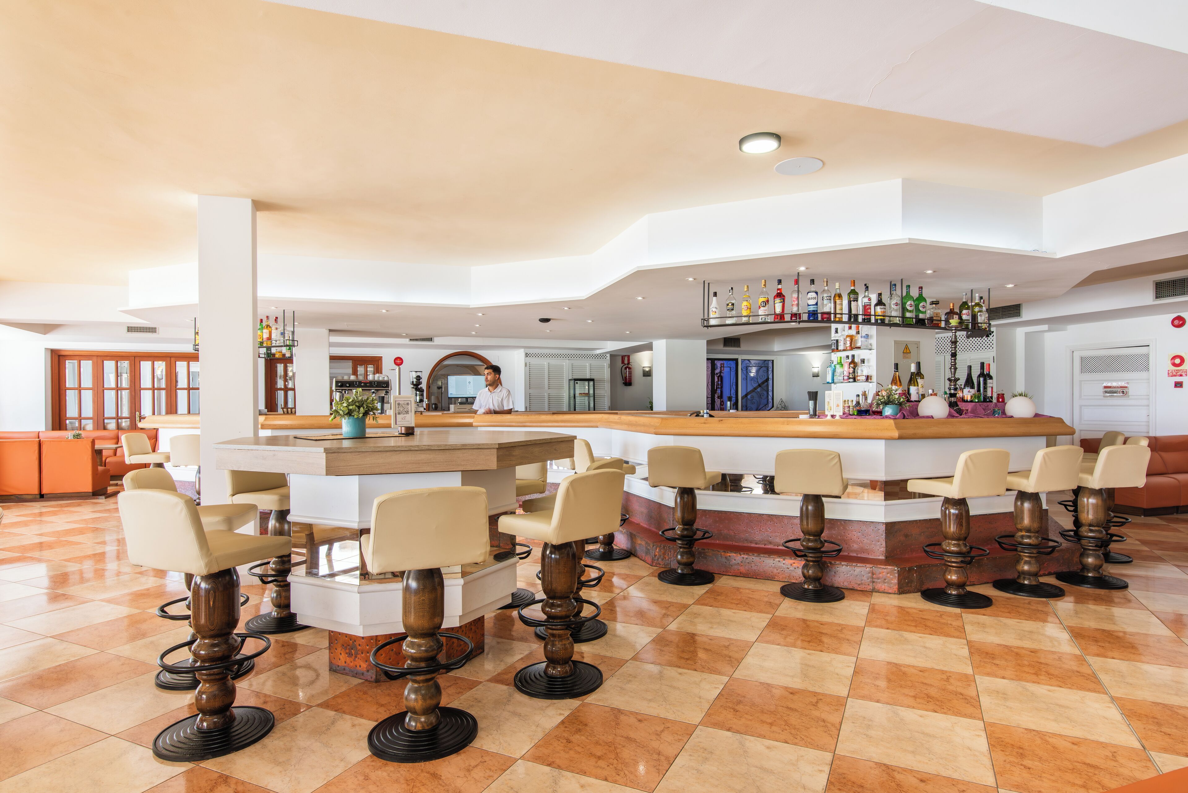 Zona de bar con varios taburetes y una barra.