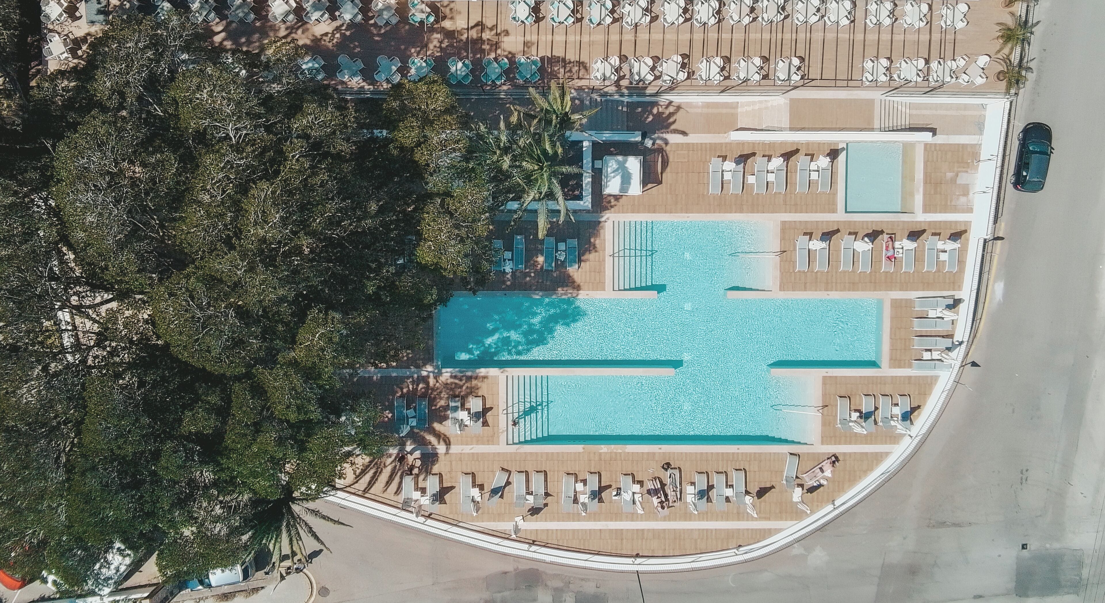 Luchtbeeld van een resort met een centraal zwembad, verschillende lounges en een parkeerplaats.