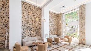 Un salón moderno con paredes de piedra, un sofá, sillones y una mesa de centro.