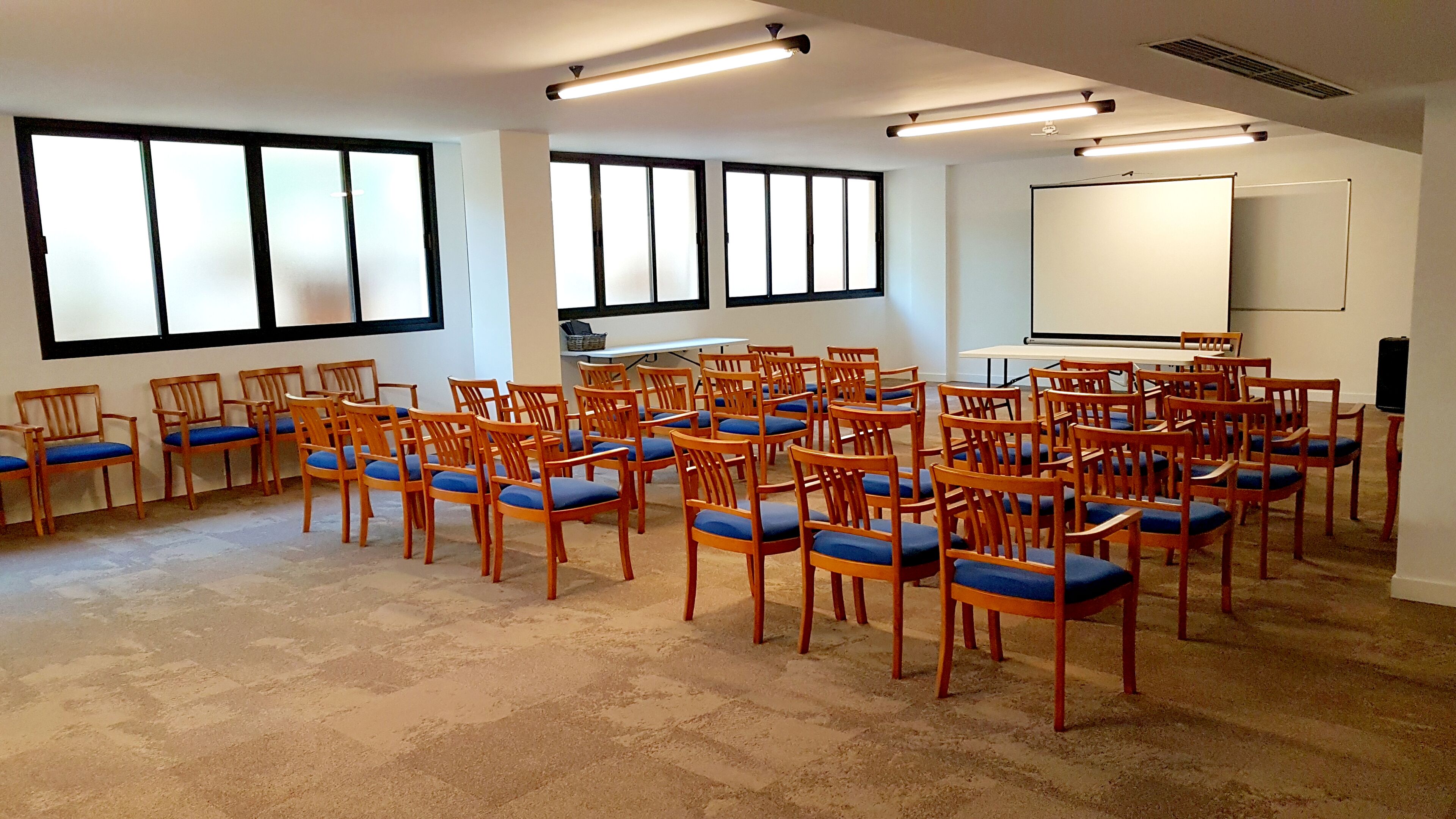 Un salón de conferencias con filas de sillas de madera y una pizarra.