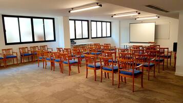 Un salón de conferencias con filas de sillas de madera y una pizarra.