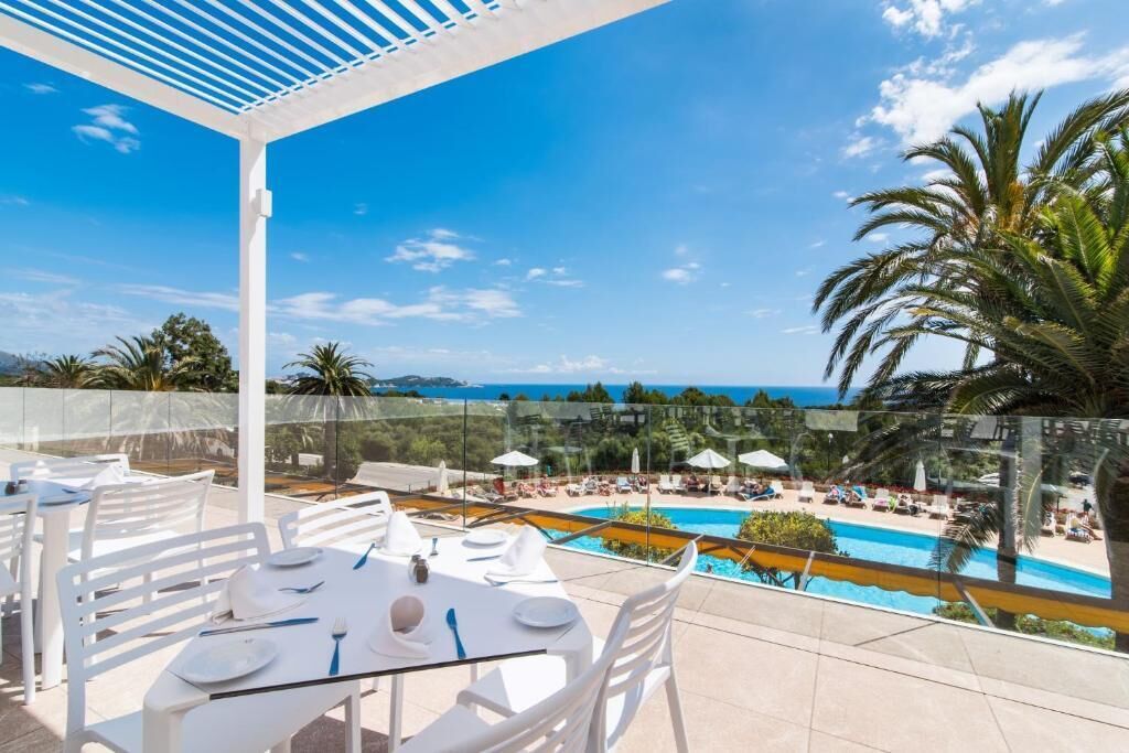 Terraza en la azotea con barandilla de cristal que da a una piscina y zona de playa.