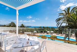Terraza en la azotea con barandilla de cristal que da a una piscina y zona de playa.