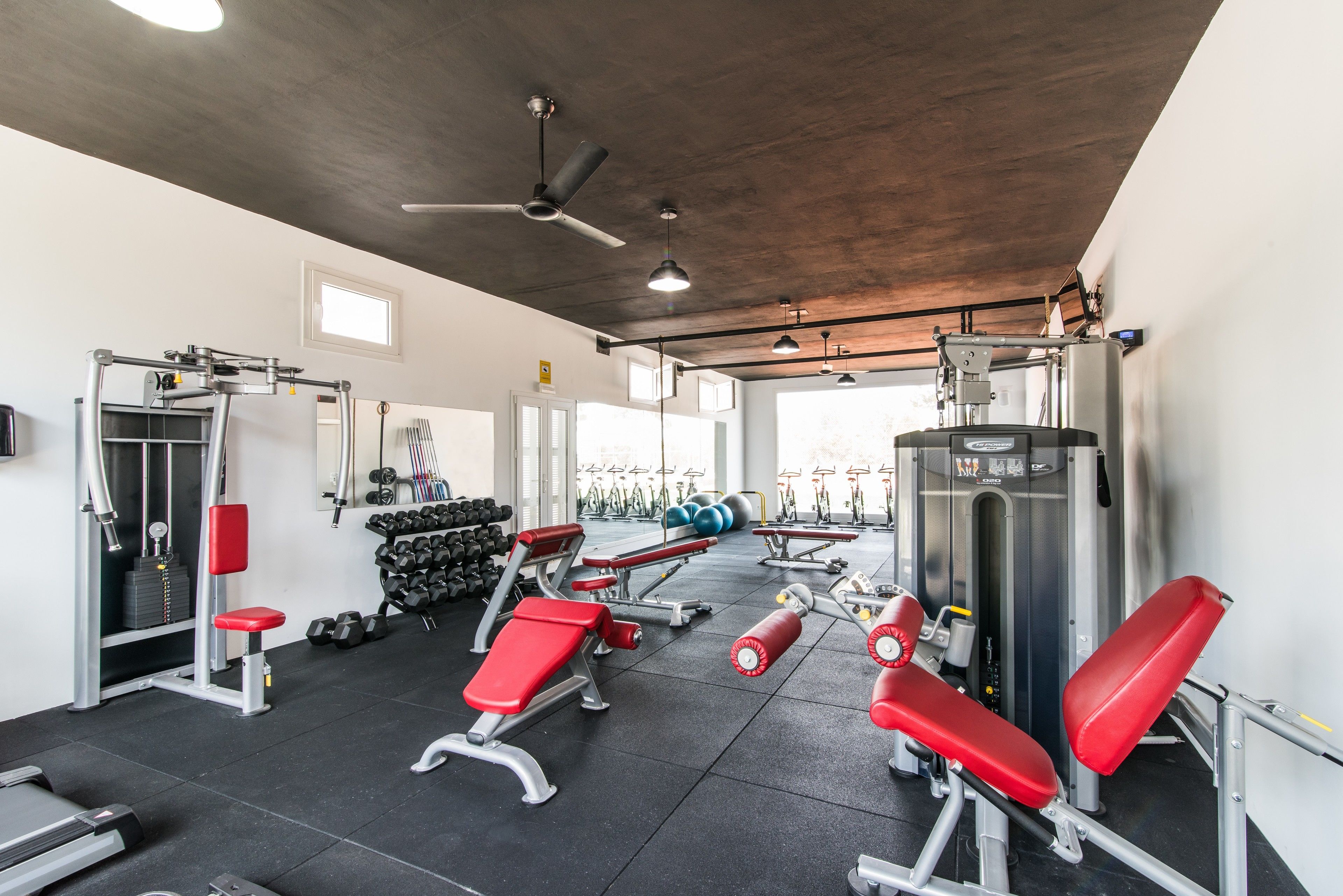 Uma academia com diversos equipamentos de exercício, incluindo bancos, halteres e máquinas de cardio.