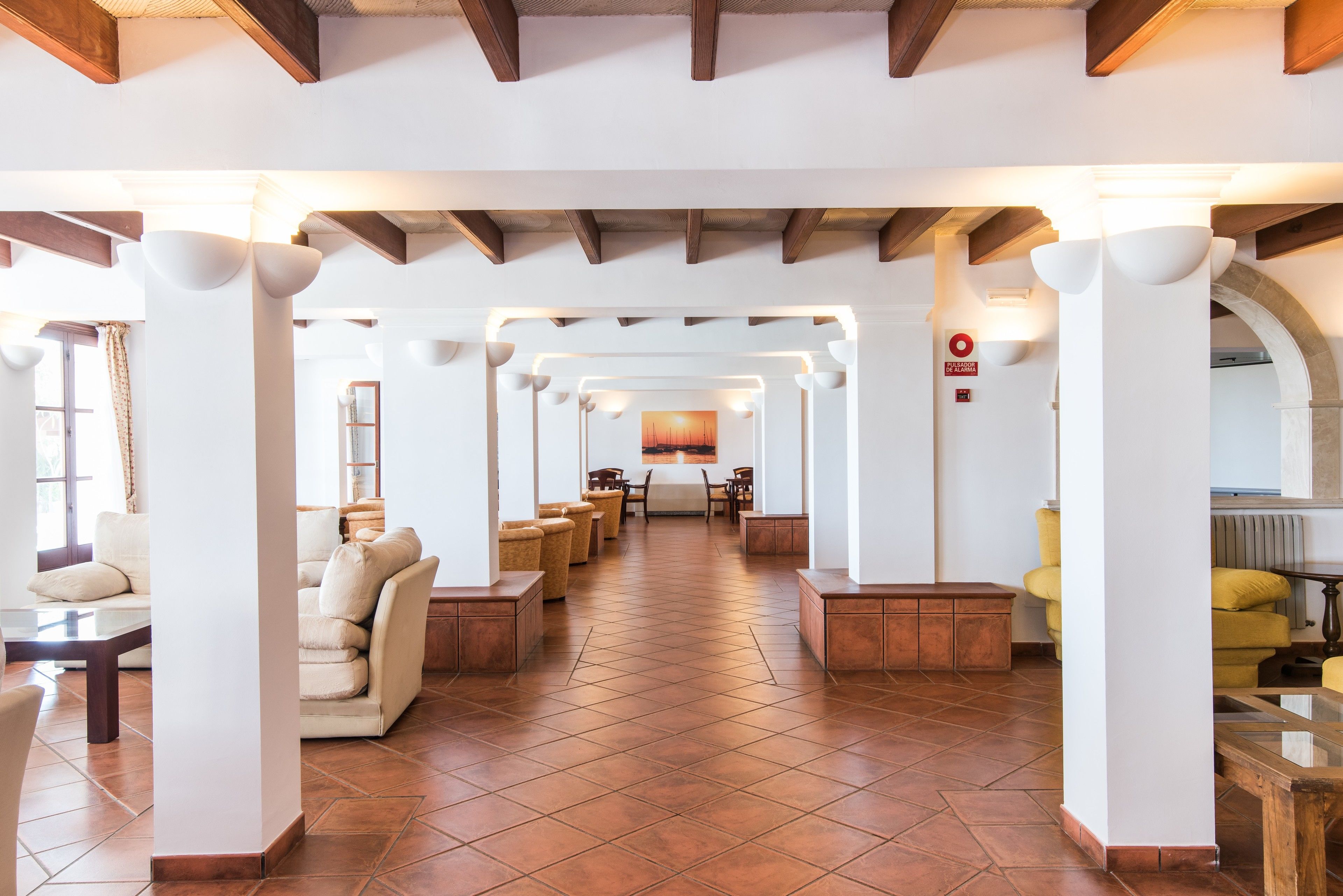 A spacious lobby with a tiled floor, multiple seating areas, and a central table.