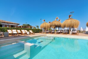 Una piscina al aire libre, sillones reclinables de piscina
