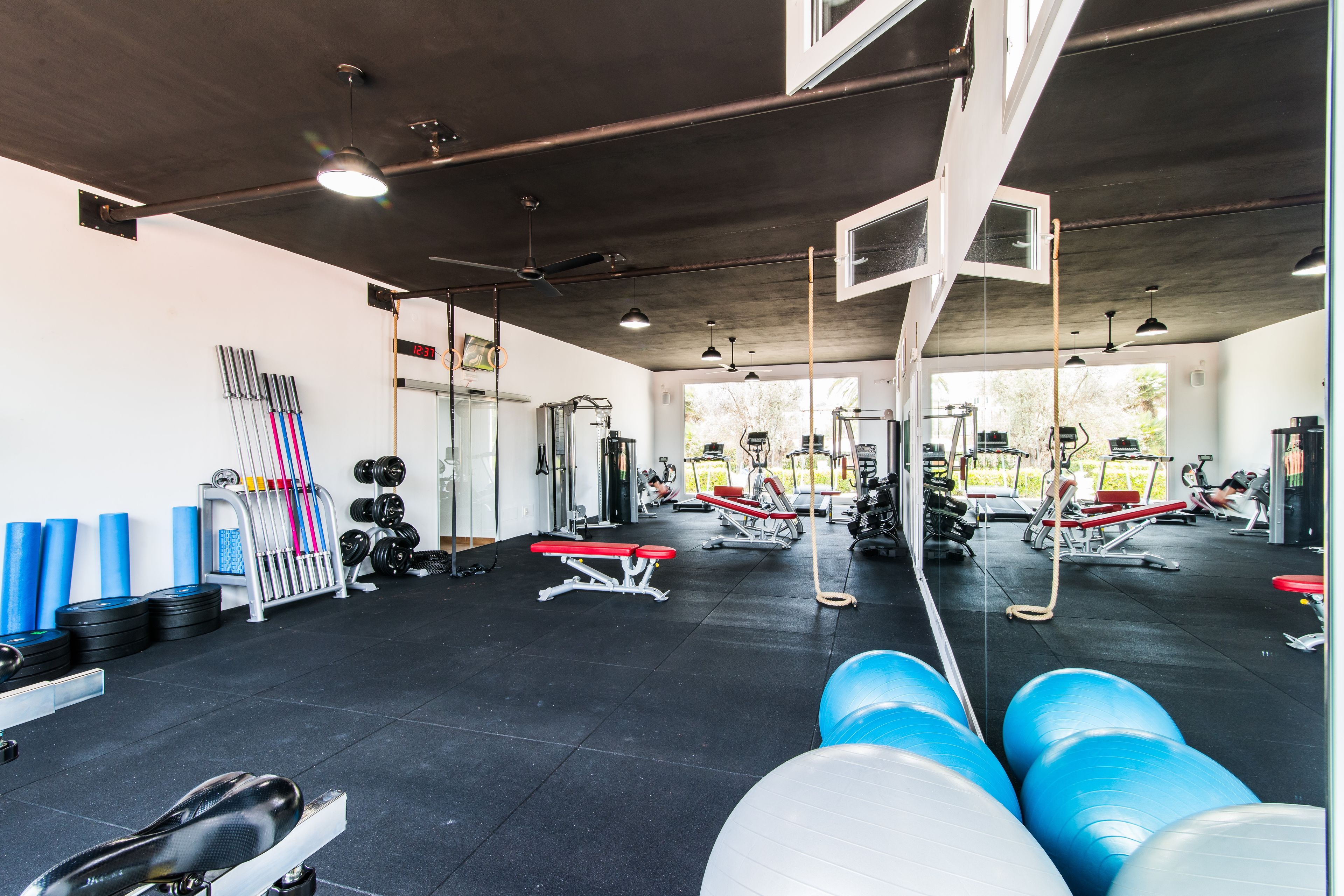A gym with various exercise equipment, including treadmills, weights, and exercise balls.