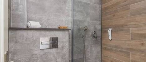 A modern bathroom with a glass shower enclosure, grey tiled walls, and a wooden accent wall.