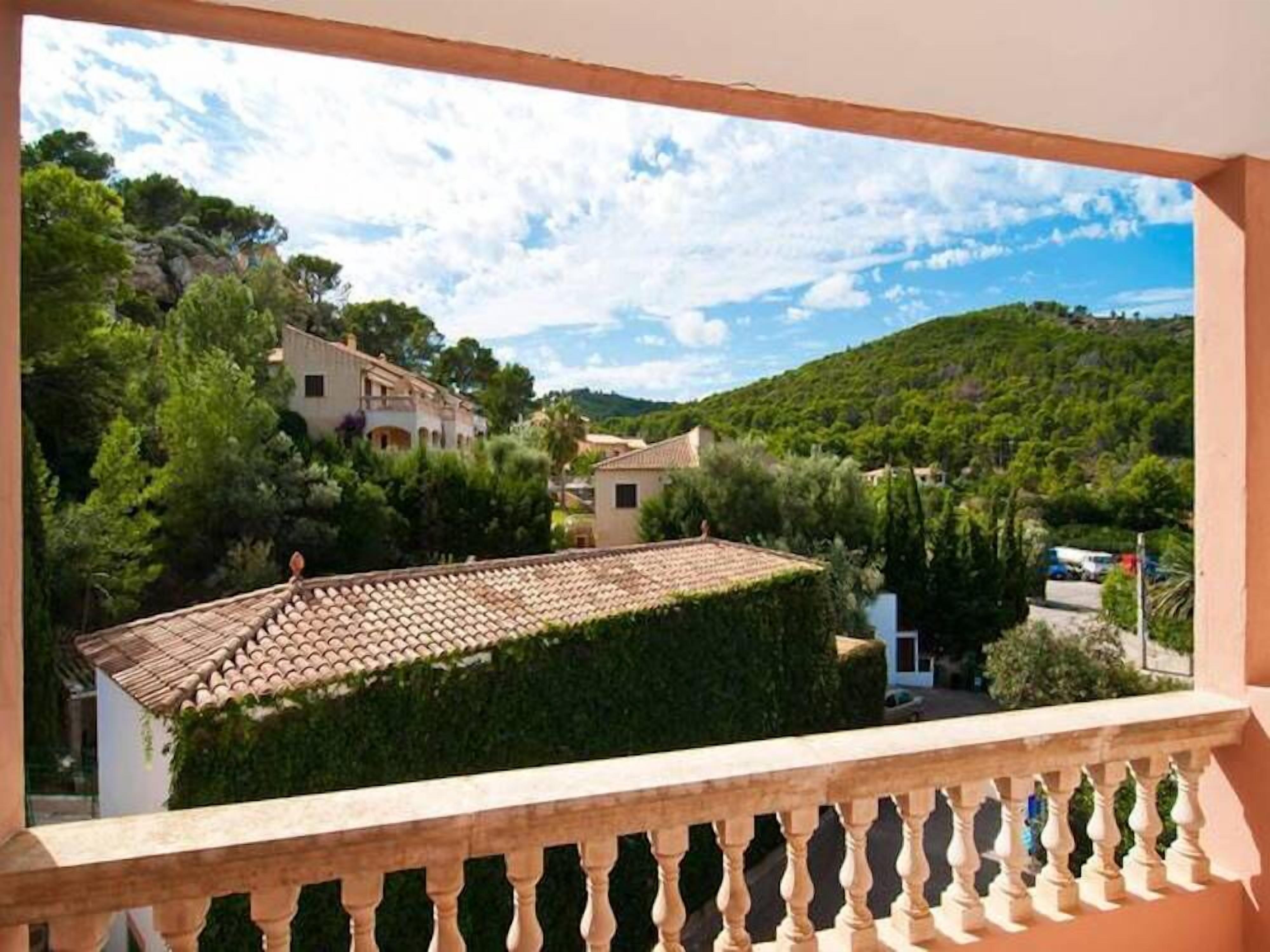 A balcony with a tiled roof overlooking a residential area with houses and greenery.