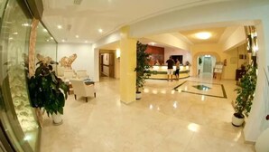 A spacious lobby with a reception desk, seating area, and potted plants. - Cala Gat (Capdepera)