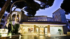 A hotel with a stone facade, arched windows, and a well-lit entrance. - Cala Gat (Capdepera)