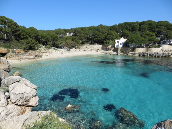 Une mer d’un bleu profond, avec des côtes rocheuses et un bâtiment blanc perché sur une colline.
