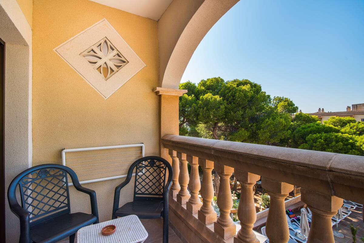 A balcony with two chairs, a table, and a decorative wall piece.
