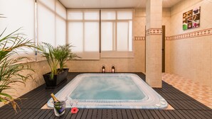 A hot tub with a tiled floor, potted plants, and a bottle of champagne. - Baviera Hotel (Capdepera)