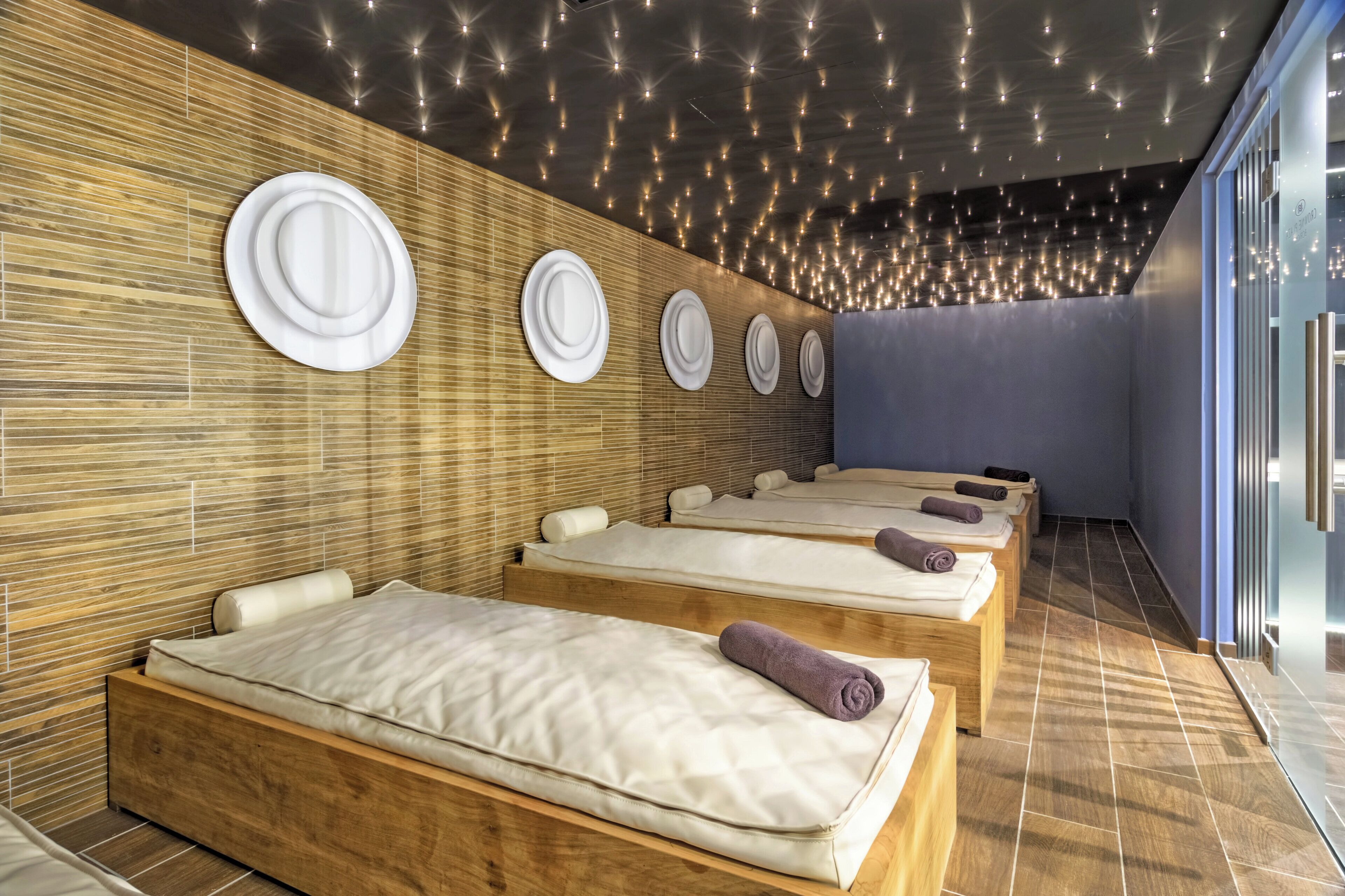 Ein Wellnessraum mit Holzwandverkleidung, mehreren Betten und Deckenleuchten.