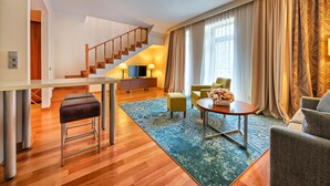 Uma sala de estar moderna com escada de madeira, um sofá, uma mesa de centro e uma televisão.
