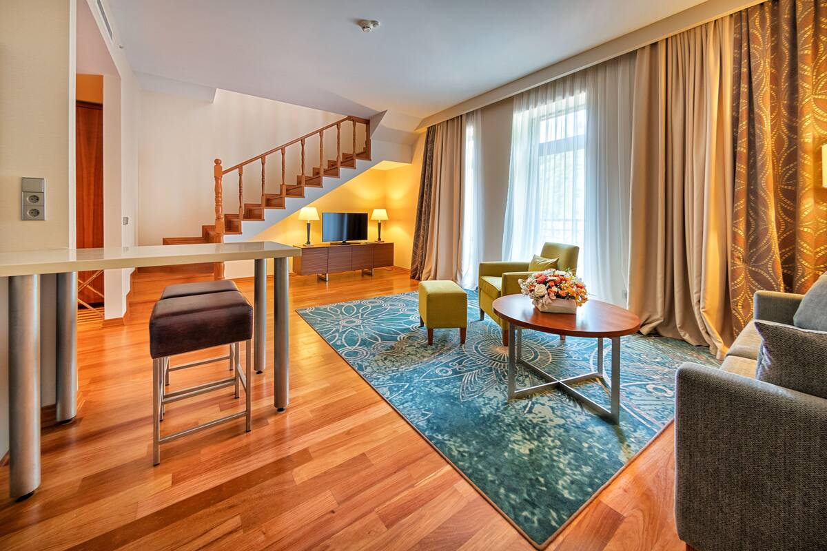 Una sala de estar moderna con una escalera de madera, un sofá, una mesa de centro y un televisor.