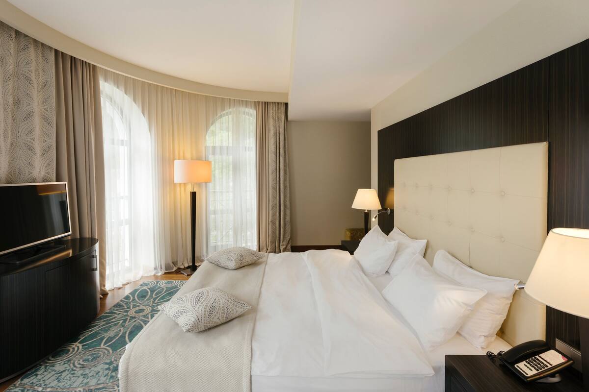 Habitación de hotel con una cama grande, dos lámparas de noche, un televisor de pantalla plana y un teléfono en la mesita de noche.