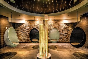 Ein modernes Interieur mit Steinwänden, Hängestühlen und einer zentralen Säule.