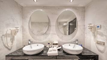 Un baño con dos lavamanos, un espejo grande y un secador de pelo en la pared.