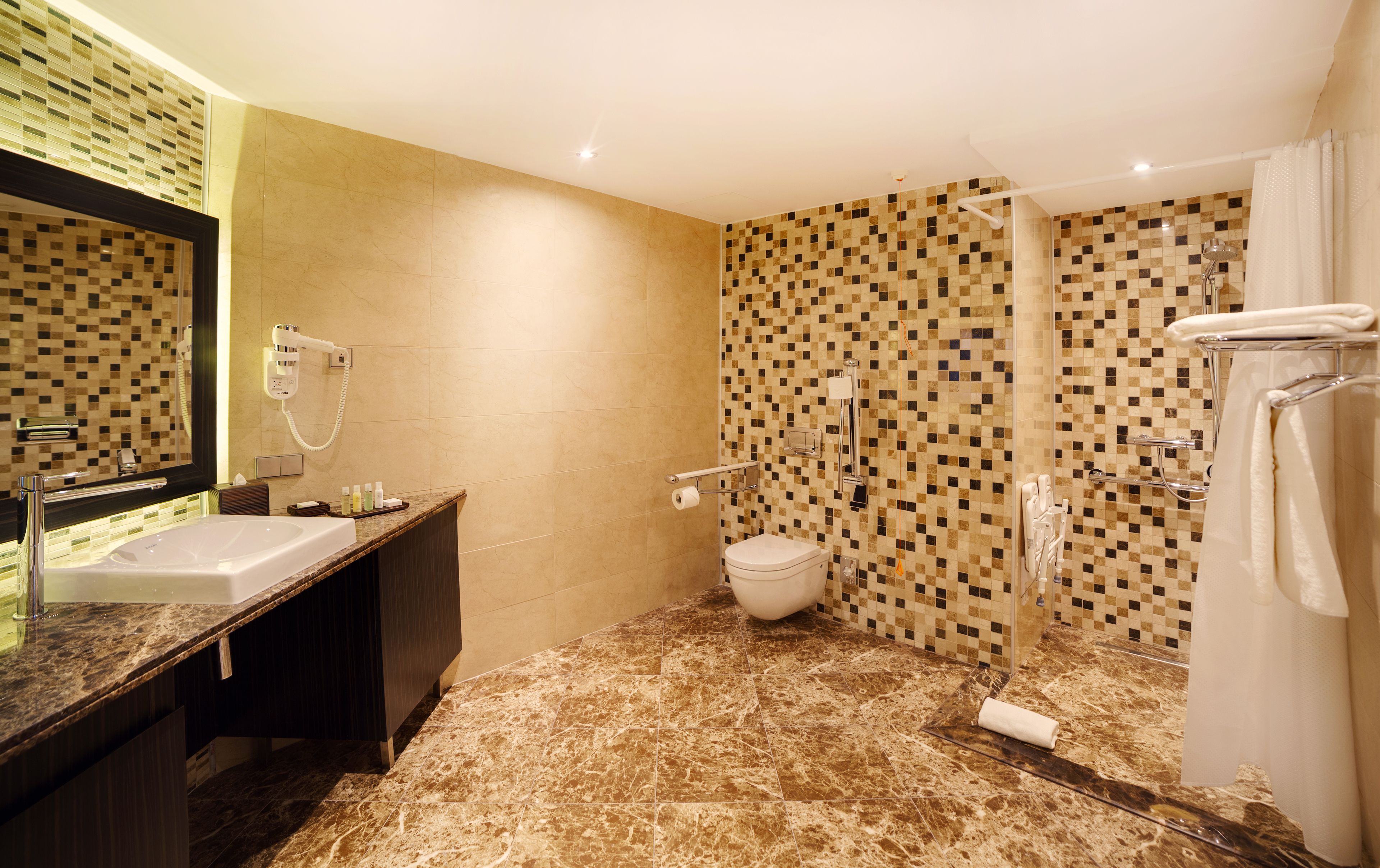 A bathroom with a sink, mirror, toilet, and shower.