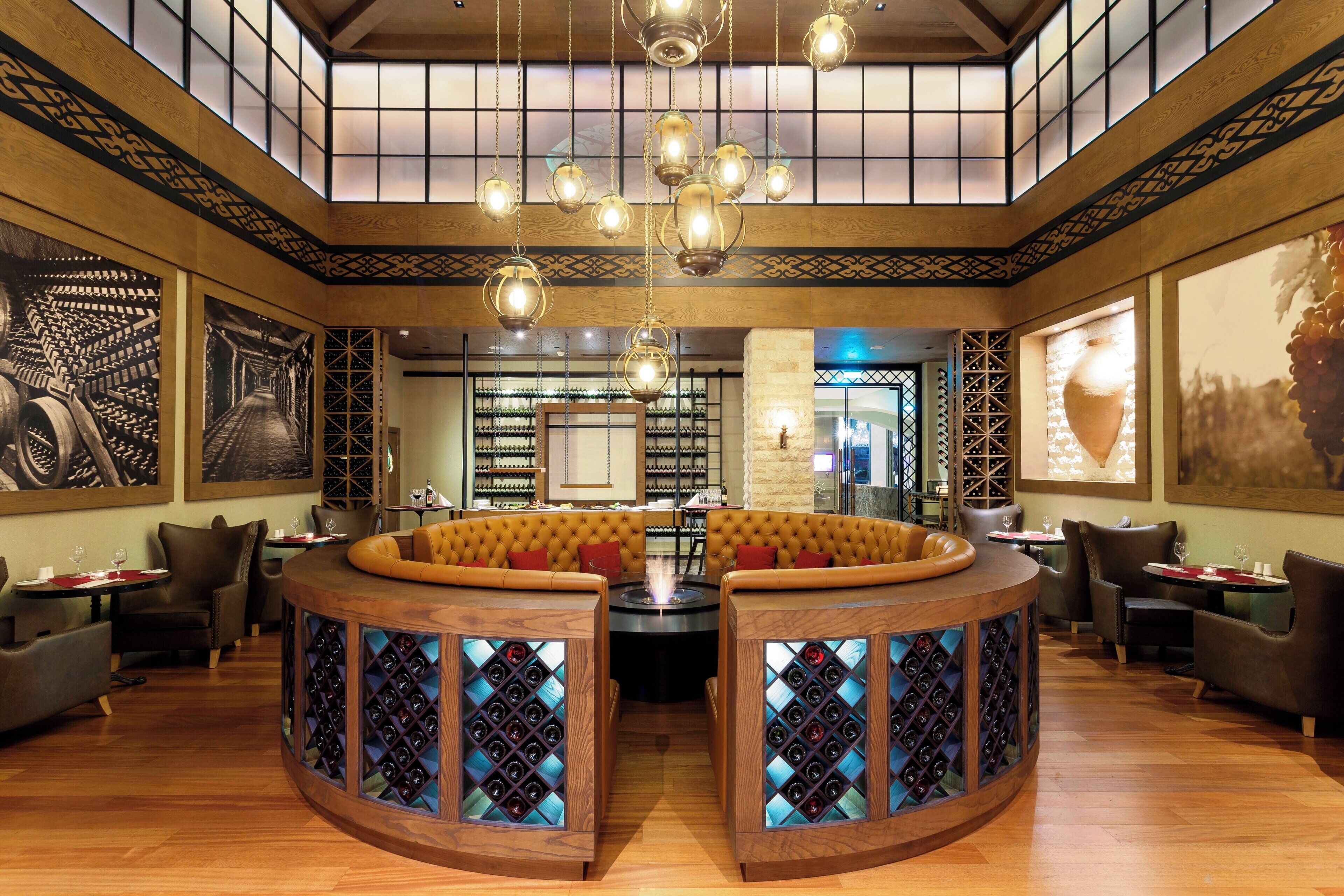 A restaurant interior with a central seating area, wine racks, and artwork on the walls.