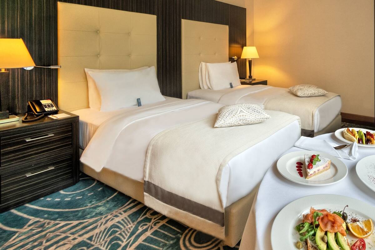 Una habitación de hotel con dos camas, un escritorio con teléfono y una mesa de comedor con platos de comida.