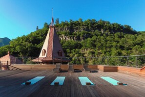 A wooden deck with exercise mats and chairs, overlooking a forested hillside. - Crowne Plaza Borjomi by IHG (Borjomi)