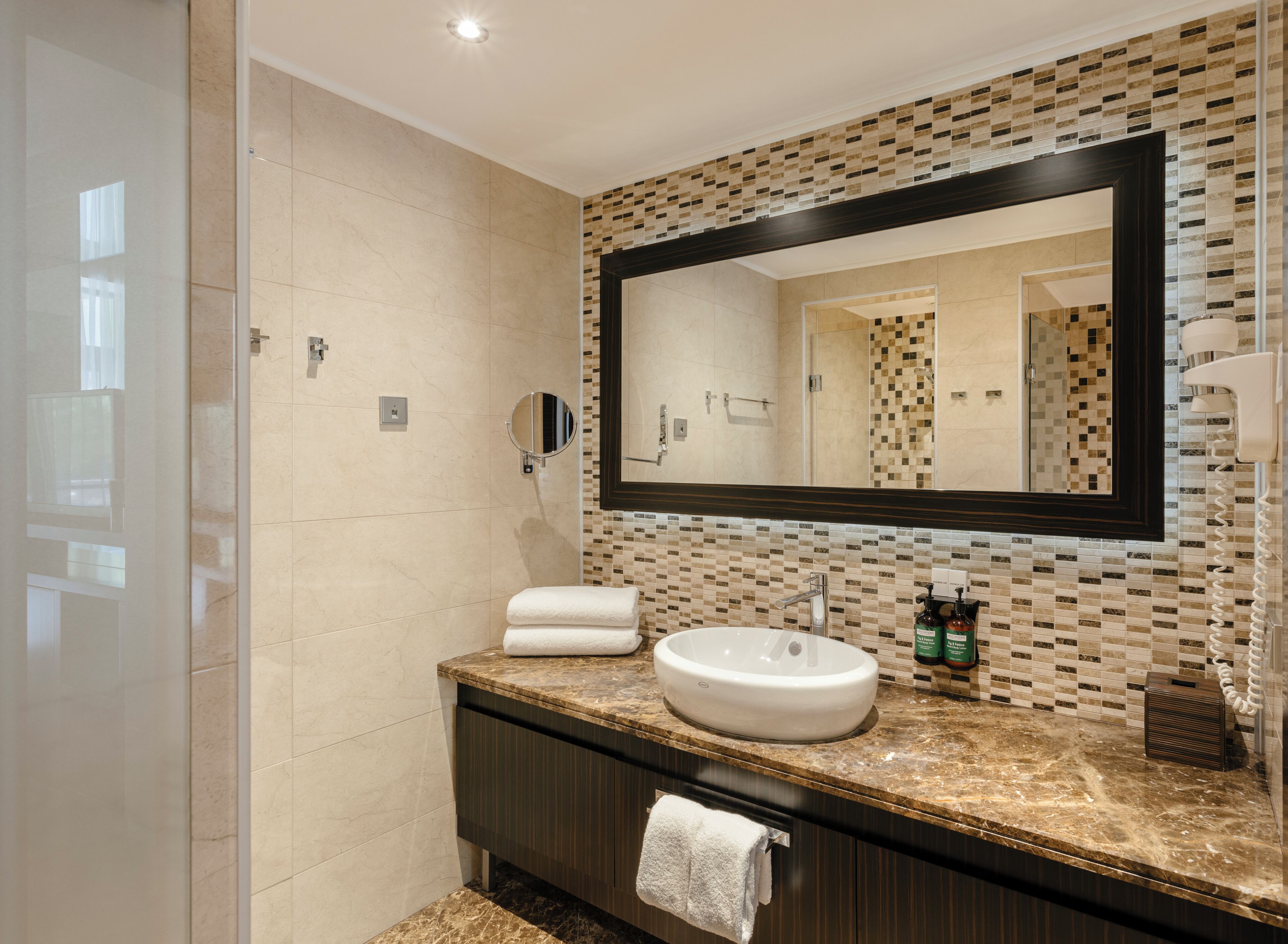 Une salle de bain moderne avec un grand miroir, un lavabo et une douche.