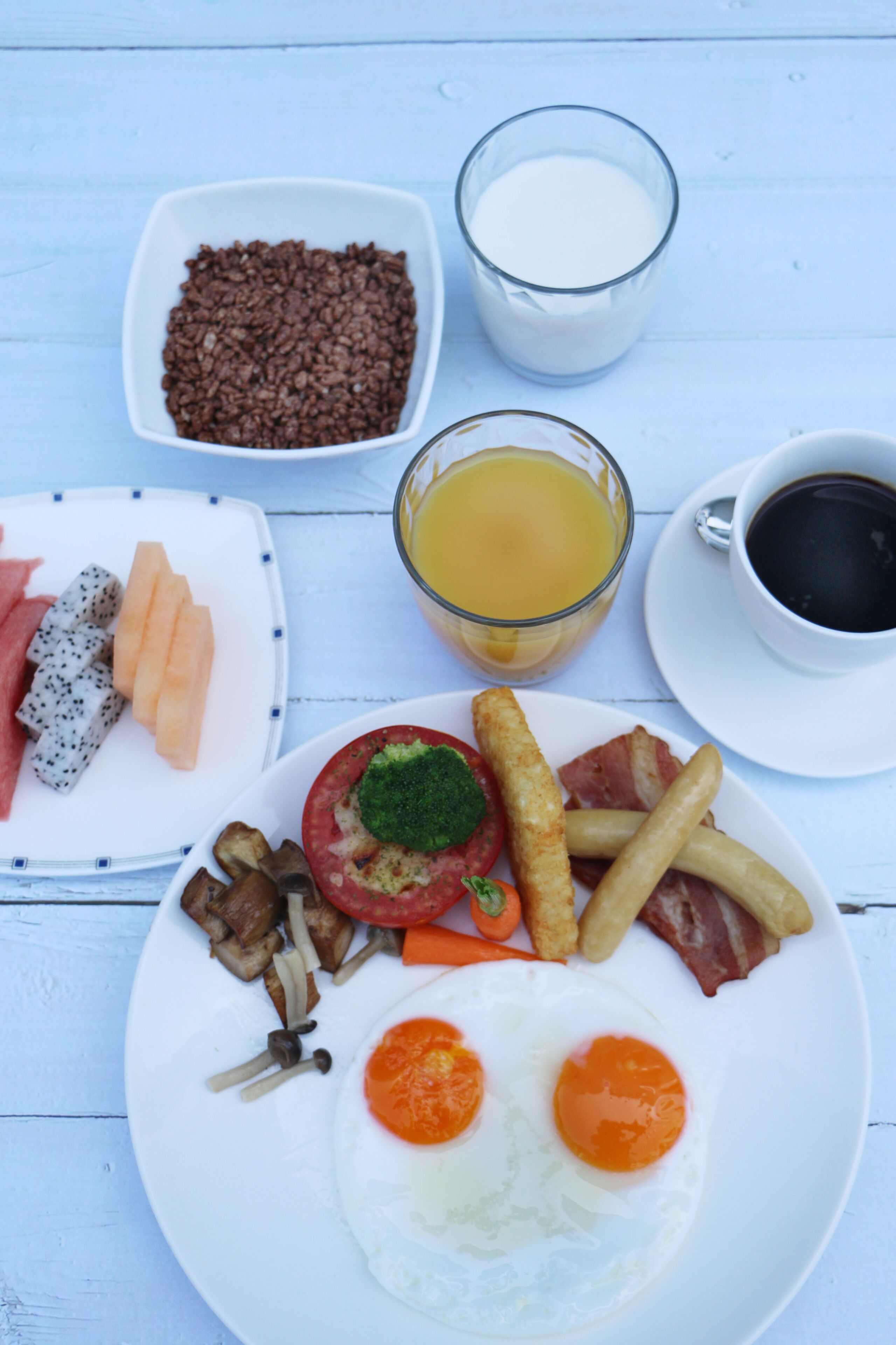 A breakfast plate with eggs, bacon, mushrooms, tomatoes, and hash browns.