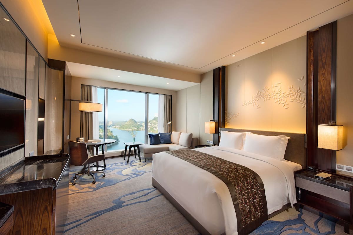 Habitación de hotel moderna con una cama grande, un escritorio, una silla y vistas a la ciudad.