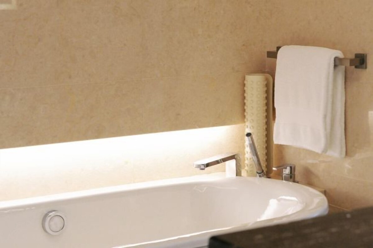 Un baño con una bañera blanca, un perchero para toallas y un dispensador de jabón.
