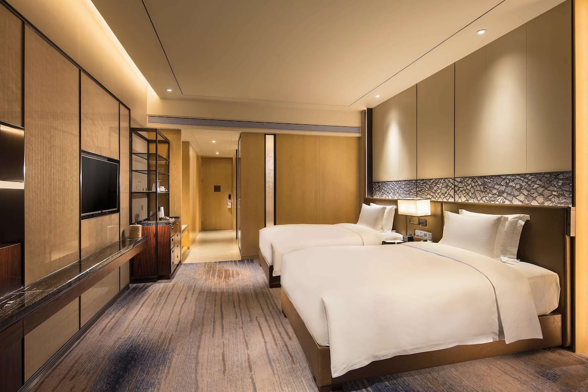 Habitación de hotel con una cama grande, televisión, minibar y baño con ducha e inodoro.