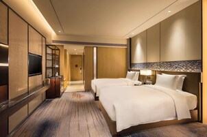 Habitación de hotel con una cama grande, televisión, minibar y baño con ducha e inodoro.