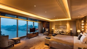 A modern hotel room with a large bed, a TV, a desk, and a view of a lake and mountains. - DoubleTree by Hilton Hotel Anshun (Anshun)