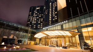 A modern hotel entrance with a glass facade, a covered entrance area, and a landscaped garden with a water feature. - DoubleTree by Hilton Hotel Anshun (Anshun)