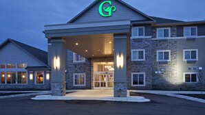 A hotel entrance with a stone facade, a covered entryway, and a prominent green logo.