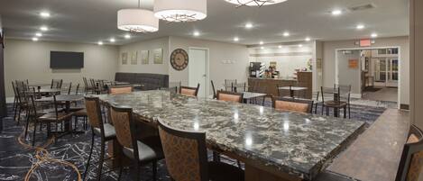 A conference room with a large marble table, multiple chairs, and pendant lighting.