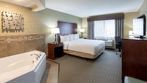 A hotel room with a large bed, a separate bathroom with a bathtub, a desk with a chair, and a television.