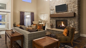 A living room with a fireplace, a sofa, a chair, a coffee table, and a TV mounted on the wall.