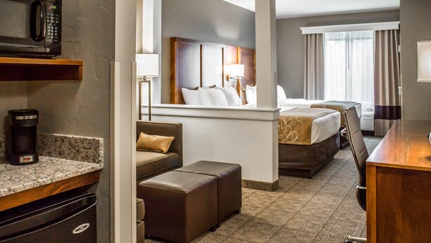 Een hotelkamer met een kitchenette, een bed met hoofdeinde, een bureau en uitzicht op het landschap.